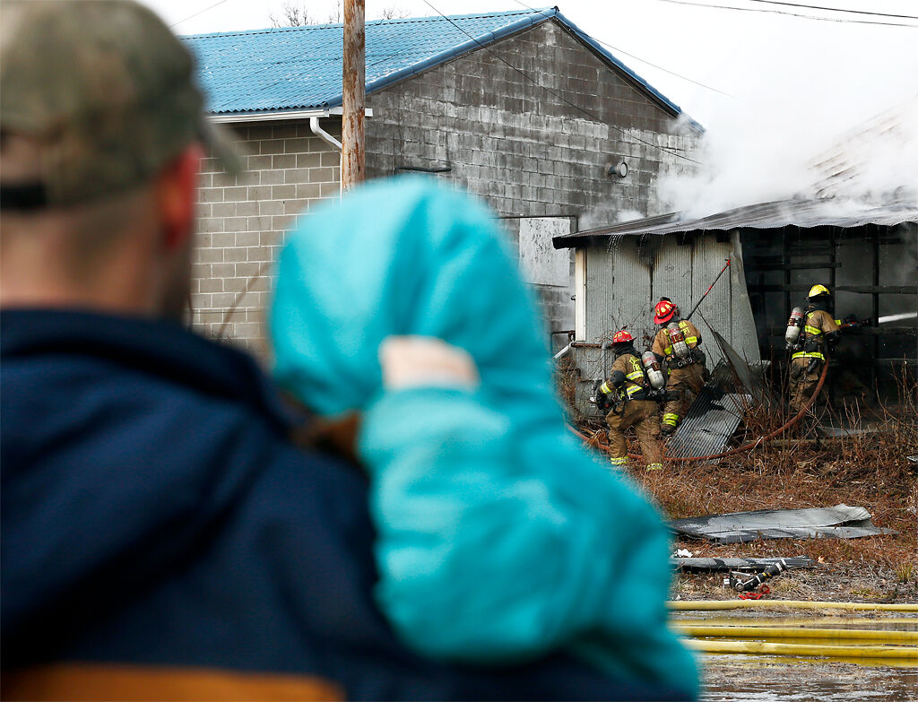 Onlookers watch as firefighters work to put out a fire
